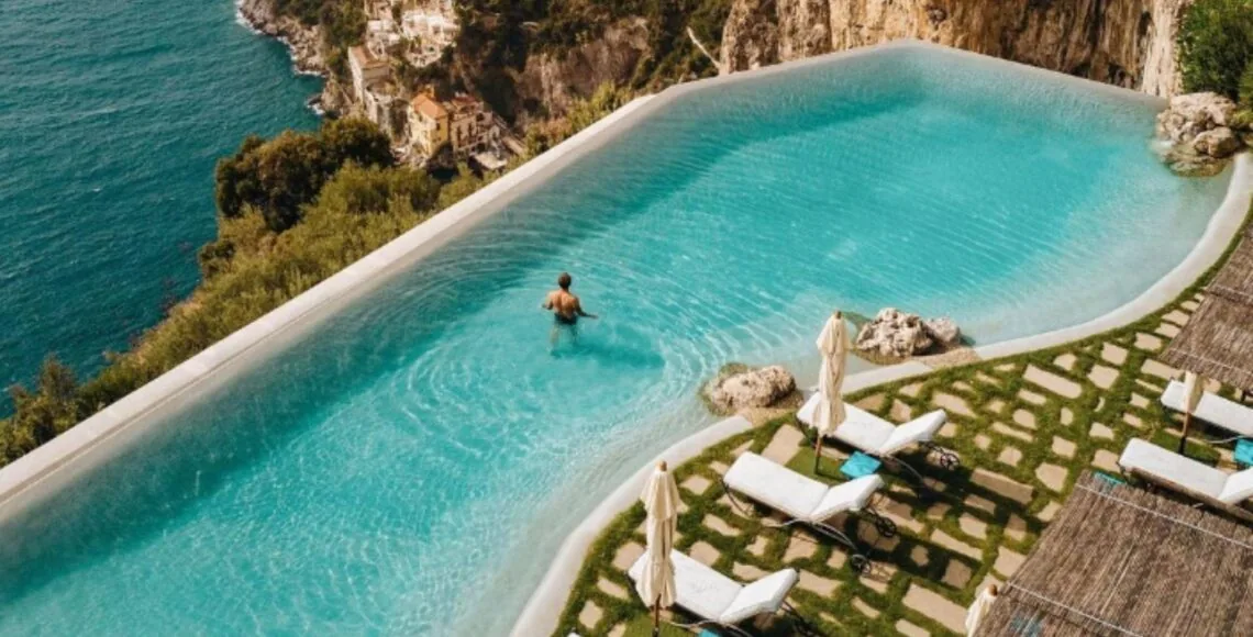 Resort-style beach-style pool with loungers and stone